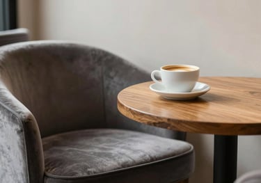 Close-up of an elegant, minimalist North American / US cafe corner with a velvet chair, a small wooden table, and a single cup of coffee, emphasizing cozy luxury.