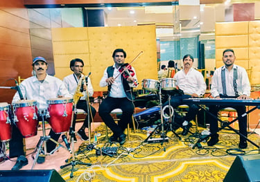 Live band musicians performing with violin, keyboard, saxophone, and conga drums at a formal event.