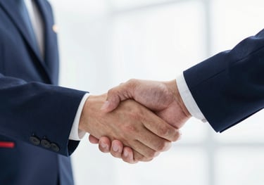 Close up of a professional handshake in a hospitality setting, with navy blue uniform accents and a bright, clean lighting style.