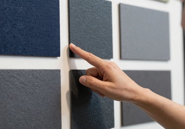 A close-up photography of a professional interior designer pointing at a mood board with textures of navy and slate, professional lighting.