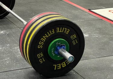 A Olympic barbell filled with bumper plates positioned on the CrossFit competition floor