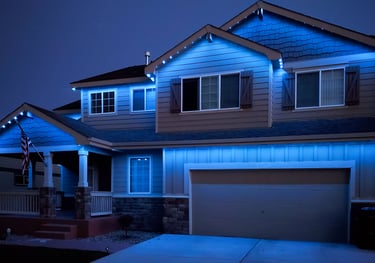 Modern two-story home with blue exterior LED trim lighting installed on the roofline and gables.