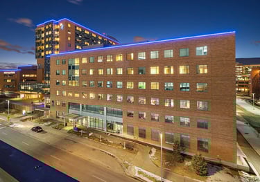 Modern brick hospital building exterior with blue LED lighting at night and glowing windows.