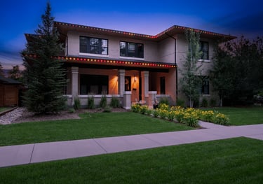 Two-story modern brick house with permanent exterior LED holiday lighting and a green lawn at dusk.