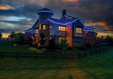 Luxury home with blue LED permanent holiday lighting on the roofline at sunset.
