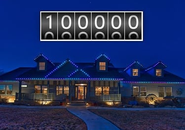 House decorated with 100,000 outdoor LED Christmas lights at night with a digital milestone counter.
