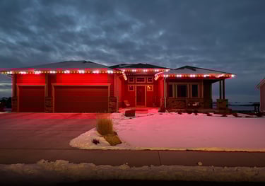 Modern ranch home featuring red and white LED roofline holiday lights on a snowy winter night.