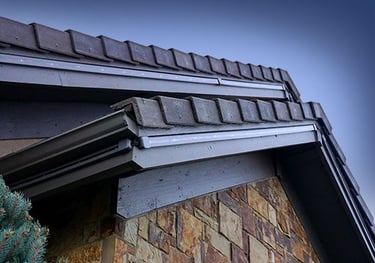 Permanent outdoor smart LED lighting tracks installed along a house roofline and stone exterior.