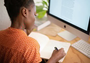a woman sitting at a desk with a notebook and pen