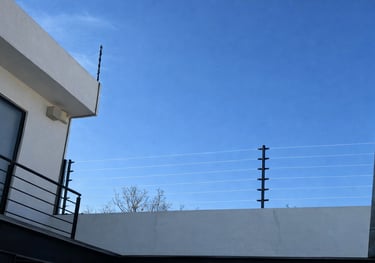 Cerco eléctrico de alto voltaje instalado en un muro perimetral residencial.