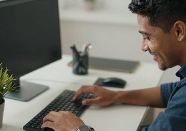 Close-up of a smiling South American / Brazilian professional working calmly at a clean, organized desk with a small plant, signifying focus and reduced stress.