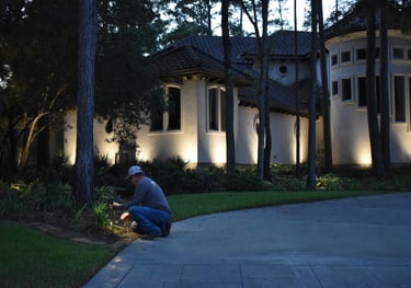 landscape lighting technician servicing a landscape light bulb