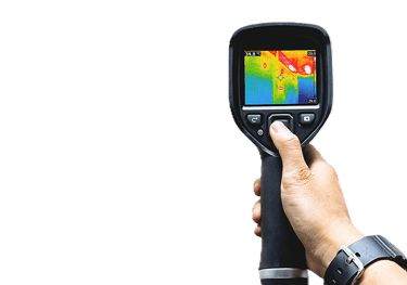 Hand holding an infrared thermal imaging camera displaying a heat map of a building interior.