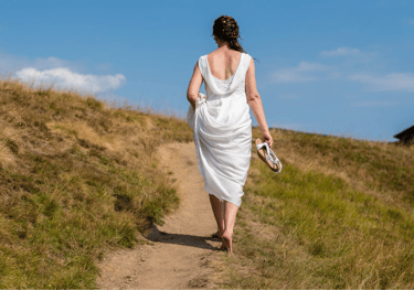 a woman in a white dress walking down a path