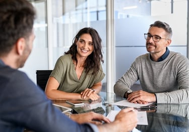 A smiling couple meeting with a professional financial advisor in a modern office to discuss business planning.