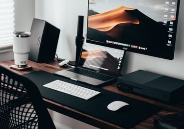 a desk with a computer monitor and a laptop