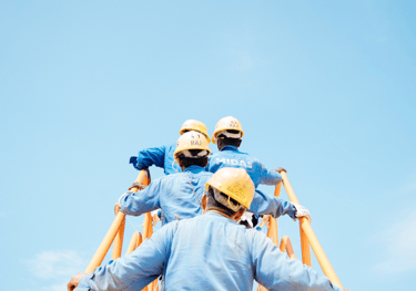 two men in blue workwears and helmets on a ladder ladder