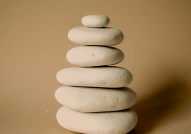 Balanced stack of smooth white zen stones for meditation and wellness on a beige background.
