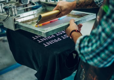 Una plancha de serigrafía con pintura de colores variados que van a ser plasmados en una camiseta.