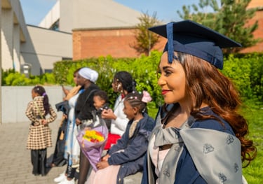 a black woman in a graduation cap and gown with her family taking lifestyle photography photos