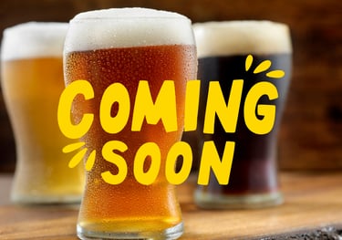 Three cold craft beers with condensation and foam under a yellow Coming Soon announcement text.