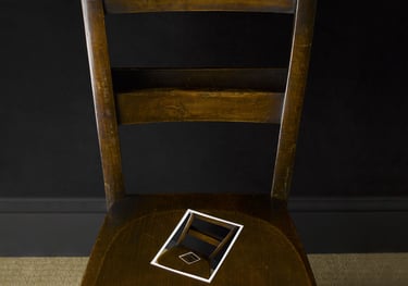 brown wooden chair against a black wall with photo of chair on its seat
