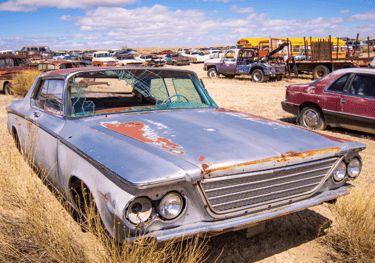 a car parked in a field with a lot of junk