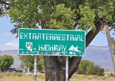a green street sign with a road sign that says extra terrestrial highway