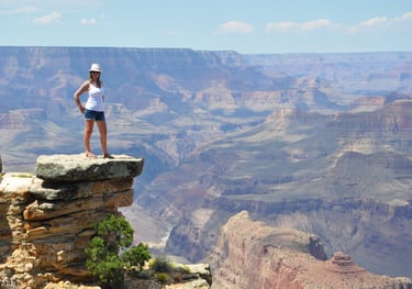 a woman standing on a cliff overlooking the grand canyon
