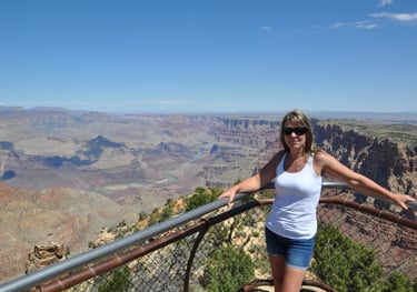 a woman standing on a railing overlooking the grand canyon