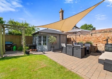 A block paved patio and outside seating area with pergola and log cabin