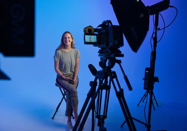 a woman sitting on a chair in front of a camera