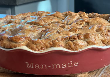 Freshly baked golden brown apple pie with a lattice crust in a red ceramic Man-made dish.