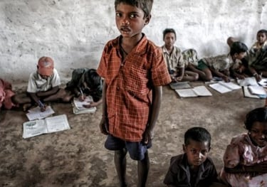 a boy standing in front of a group of children in a class room