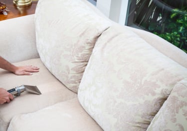 a man cleaning a couch with an extractor wand