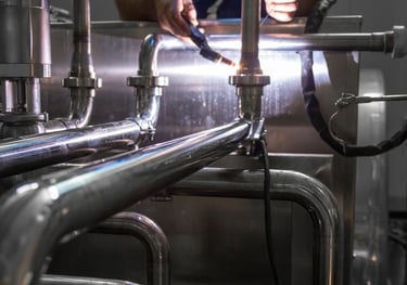 a man welding a stainless steel pipe in a factory