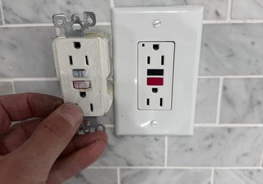 a person holding a white electrical outlet in a white tiled wall