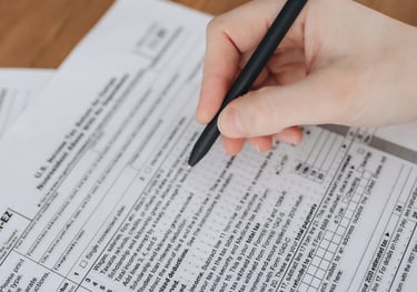 une main tenant un stylo, remplissant un formulaire.