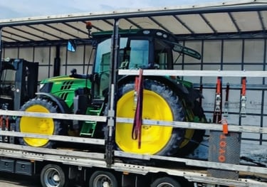 grüner Traktor mit gelben Rädern auf LKW