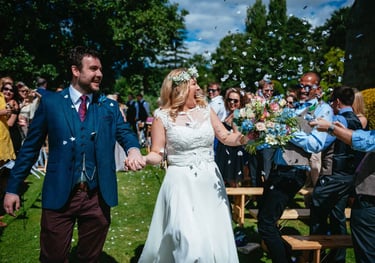 Confetti joy as the couple walk hand in hand at Brinsop Court Manor House and Barn, surrounded by smiling guests.