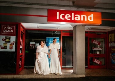 a couple of bridesmaid standing in front of an Iceland Food store
