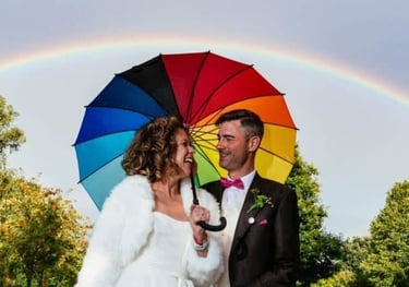 a bride and groom standing under a rainbow - colored rainbow - colored rainbow - colored