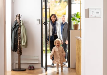 Family coming home with security panel on wall