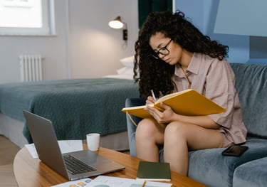 a woman sitting on a couch with a laptop and a notebook