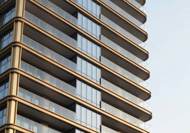 Sleek architectural facade of a modern luxury high-rise in Gurgaon, showcasing premium glass balconies, crisp lines, and rich gold-finished metallic framework under a bright, clean sky. Professional real estate showcase.