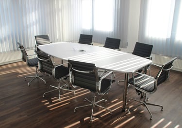 Een lege tafel met stoelen in zacht licht, symbool voor ruimte om samen te reflecteren.