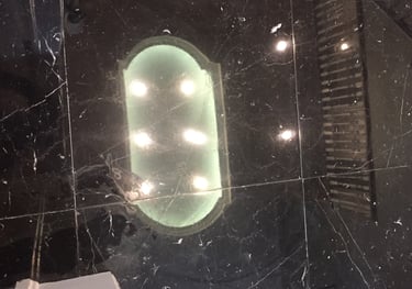 Overhead lighting and upper floor railing reflected right back in shinny black marble flooring