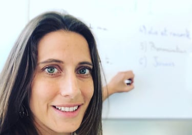 a woman French teacher standing in front of a white board she tutors French class