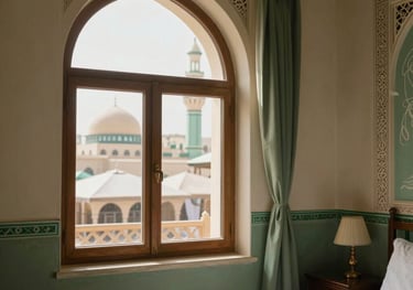 Photography of a peaceful hotel room in Madinah. The window offers a glimpse of the Prophet's Mosque umbrellas. The room is decorated in sage green and cream tones with traditional mashrabiya details.