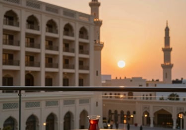 A modern hotel balcony in Madinah at sunset. The sky is a soft orange. A small table with a glass of tea sits in the foreground. Professional travel photography with Islamic architectural patterns in view.